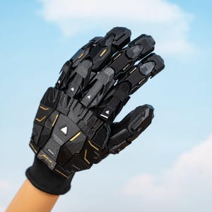 K&ouml;nnte beinhalten: Schwarzer Roboterhandschuh mit geometrischen Formen und goldenen Akzenten. Der Handschuh wird auf einer Hand vor blauem Himmel getragen. Das Design weist gegliederte Segmente und eine strukturierte Oberfl&auml;che auf, was auf ein futuristisches oder Cosplay-Thema hindeutet.