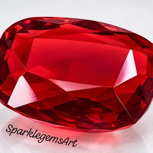 Puede incluir: Una gema roja vibrante de corte cojín con una superficie facetada que refleja la luz, creando profundos reflejos y sombras carmesí. La piedra presenta un acabado pulido y se muestra con el texto SparklegemsArt impreso en color negro debajo.