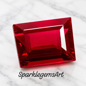 Könnte beinhalten: Ein rechteckiger, facettierter roter Edelstein mit scharfen Kanten und einer polierten Oberfläche. Der Stein zeigt tiefe karmesinrote Farbtöne und interne Lichtreflexionen. Der Text SparklegemsArt ist in schwarzer Schrift unter dem Edelstein gedruckt.