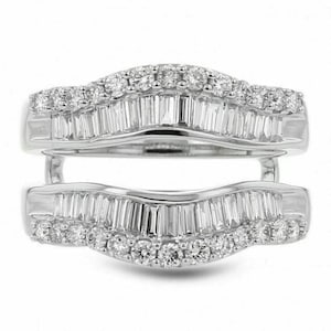 May include: A silver-toned ring guard featuring two curved bands connected at the sides. Each band is set with a row of baguette-cut stones in the center, flanked by a row of small round-cut stones along the outer edges, creating a layered look.