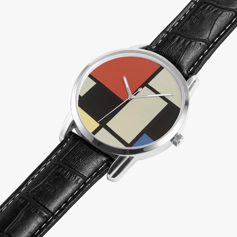 May include: A wristwatch with a silver case and a black leather band. The watch face features a geometric design with red, black, yellow, beige, and blue shapes. The watch has silver hands and a crown on the side.