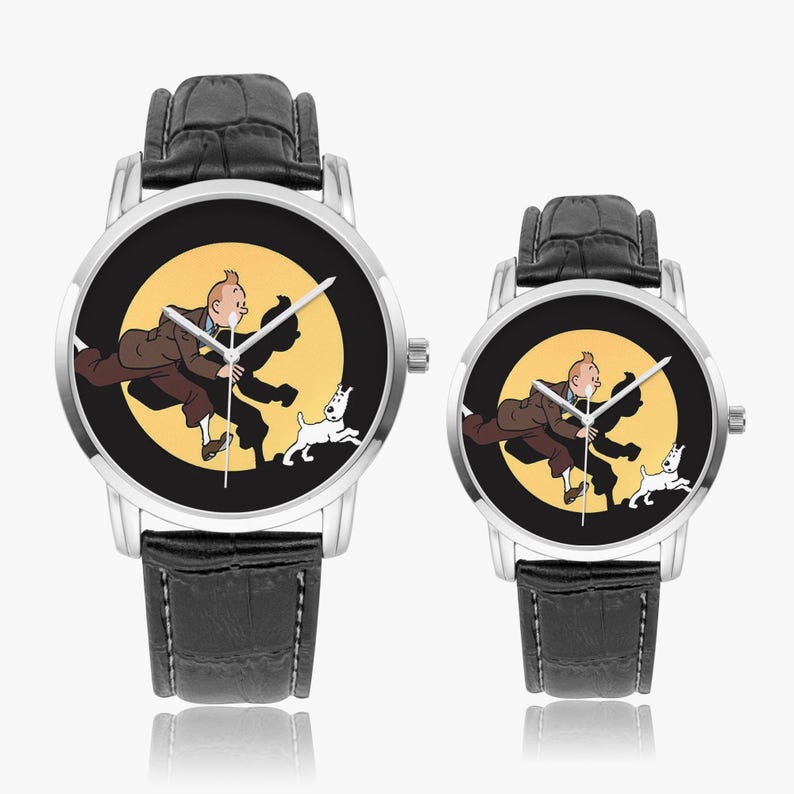 Op de afbeelding: Twee polshorloges met zwarte leren bandjes en zilveren kasten. De wijzerplaten tonen een cartoonillustratie van een man, een hond en een gele achtergrond. De horloges hebben verschillende maten.