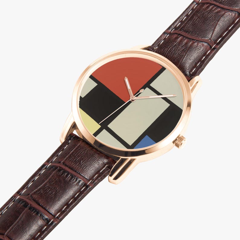 May include: A gold-tone wristwatch with a brown leather band. The watch face features a geometric design with red, black, white, yellow, and blue blocks. The band has a textured, crocodile-like pattern.