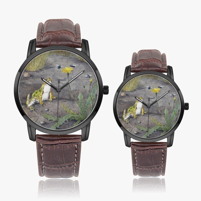 May include: Two black-cased watches with brown leather straps. The watch faces feature a frog, a dandelion, and insects on a stone surface. The watches are of different sizes.