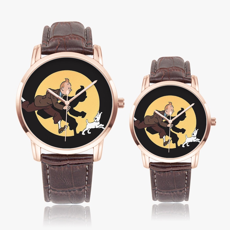 Op de afbeelding: Twee ros&eacute;gouden horloges met bruine leren bandjes. De wijzerplaten van de horloges tonen een cartoonillustratie van een man, een hond en een gele achtergrond. De wijzers van het horloge zijn zwart.