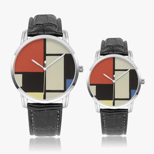 May include: Two wristwatches with black leather bands and silver-toned cases. The watch faces feature a colorful geometric design with red, black, white, and blue blocks. The watches are displayed on a white surface.