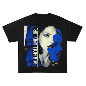 May include: Black t-shirt featuring a graphic from the film "Mulholland Dr." The design includes a portrait of a woman with blue and white accents, the film's title, and the names of the actors. The shirt is a classic crew neck style.
