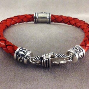 May include: A red leather braided bracelet with silver toned metal accents and a clasp closure.