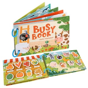 May include: A colorful children's "Busy Book" with the text "Hello! Alphabet!" features farm animals and fruits and vegetables. The book has blue ring binding and includes removable animal and food pieces for interactive play.