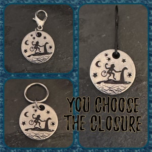 May include: Silver charm with a monkey riding a sea serpent, surrounded by stars and a crescent moon. You choose the closure: key ring or lobster clasp.
