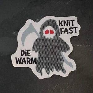 May include: A white sticker with a black and gray illustration of the Grim Reaper wearing a knitted hooded robe. The text "Knit Fast Die Warm" is printed on the sticker.