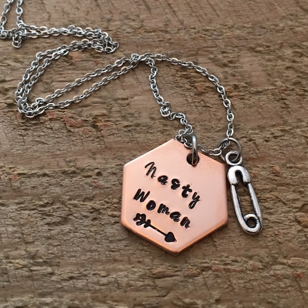 Hand stamped "nasty woman" necklace with safety pin charm.