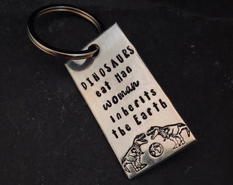 Hand stamped "Dinosaurs eat man woman inherits earth” keychain.