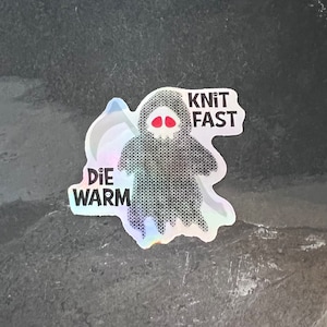 May include: A black and white sticker with a cartoon ghost wearing a knitted sweater. The sticker says "Knit Fast Die Warm" and has a holographic effect.