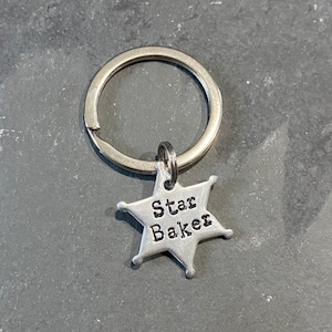 May include: Silver keychain with a star-shaped charm that says "Star Baker" on it.