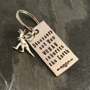 Hand stamped "Dinosaurs eat man woman inherits earth” keychain.