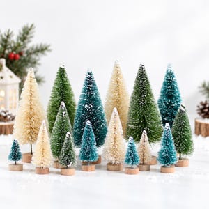 Könnte beinhalten: Eine Sammlung von Miniatur-Flaschenbürstenbäumen in verschiedenen Grün-, Creme- und Weißtönen. Jeder Baum hat eine strukturierte, borstige Oberfläche und ist auf einem kleinen, runden, hellen Holzsockel montiert, was ein abwechslungsreiches Wald-Display ergibt.