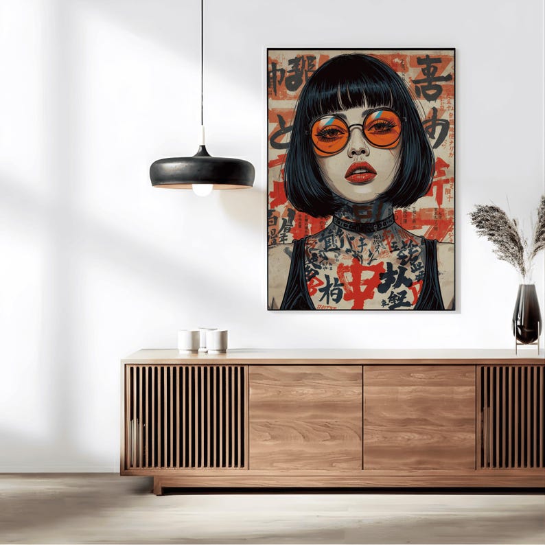 K&ouml;nnte beinhalten: Ein gerahmter Kunstdruck mit einer Frau mit schwarzen Haaren und orangefarbenen Gl&auml;sern. Das Kunstwerk hat eine japanische &Auml;sthetik mit rotem und schwarzem Text im Hintergrund und T&auml;towierungen am Hals und an der Brust der Frau. Der Druck wird &uuml;ber einem Holzschrank ausgestellt.