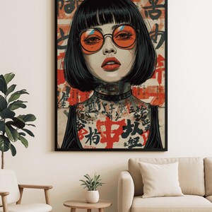 K&ouml;nnte beinhalten: Gerahmter Kunstdruck mit einer Frau mit schwarzen Haaren, orangefarbener Sonnenbrille und T&auml;towierungen. Das Kunstwerk hat einen roten und beigen Hintergrund mit japanischen Schriftzeichen. Die Frau tr&auml;gt ein schwarzes Oberteil. Der Druck wird in einem Wohnzimmer gezeigt.