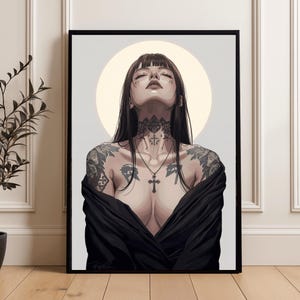 Peut inclure: Impression d'art encadrée représentant une femme aux longs cheveux noirs, tatouages et pendentif en forme de croix. L'œuvre a une qualité douce et éthérée avec un fond clair et un cadre noir. La femme porte un vêtement noir.