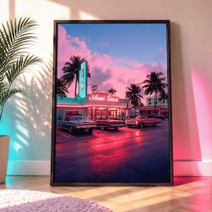 Op de afbeelding: Ingelijste print van een Miami Beach-scène bij zonsondergang. De afbeelding toont een retro diner met een neonreclame, palmbomen en klassieke auto's. De lucht is een mix van roze, blauwe en paarse tinten, die reflecteren op het natte wegdek.