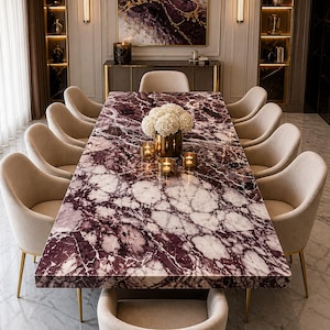 May include: An opulent dining room with a large rectangular table. The table has a striking purple and white marble top. Ten beige upholstered chairs with gold legs surround the table. A chandelier hangs above, and the room is decorated with artwork and lighting.