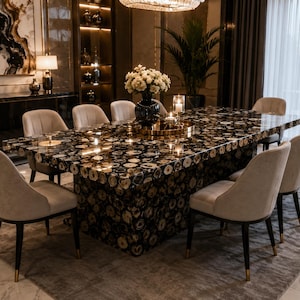 May include: A rectangular dining table featuring a surface and base composed of polished black and white agate stone slices. The table is surrounded by eight upholstered chairs with light beige fabric, dark wooden legs, and gold-toned metal accents.