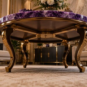 May include: A round coffee table featuring a polished purple amethyst gemstone top with a natural crystalline texture. The table is supported by four curved, gold-toned metal legs that connect to a central circular metal base plate.