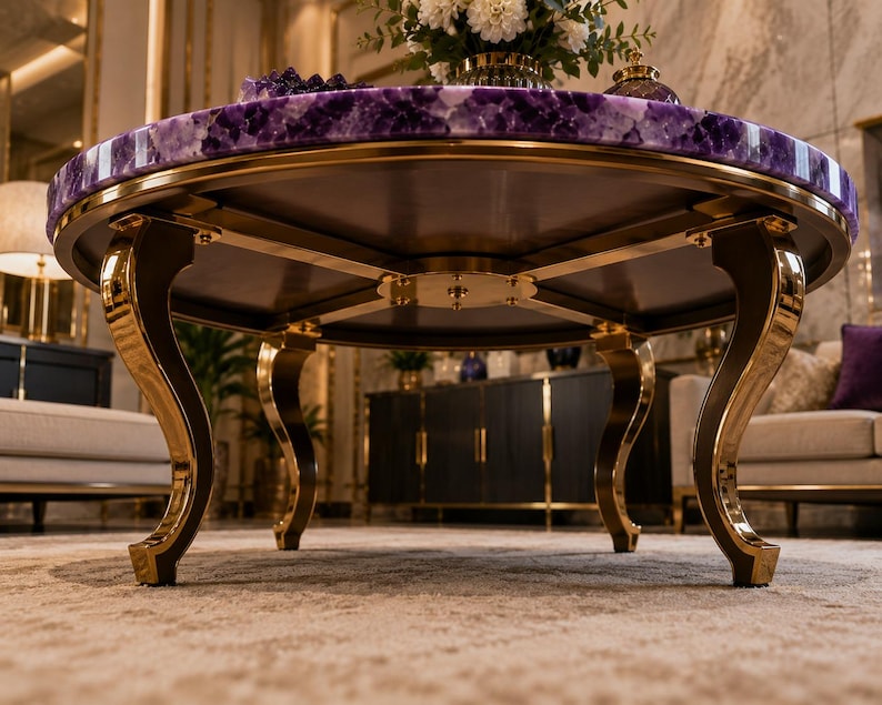 May include: A round coffee table featuring a polished purple amethyst gemstone top with a natural crystalline texture. The table is supported by four curved, gold-toned metal legs that connect to a central circular metal base plate.