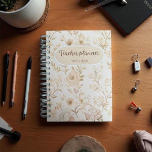 May include: A cream and beige floral teacher planner, spiral-bound, with the text "Teacher planner 2025/2026" on the cover. The image includes pens and small accessories on a wooden surface. The planner is designed for the academic years 2025 and 2026.