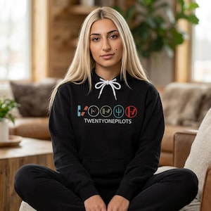 May include: Black hoodie with a white drawstring and the text "TWENTYONEPILOTS" in a colorful graphic design. The design includes various symbols in teal, yellow, blue, and red. The person is wearing black pants.