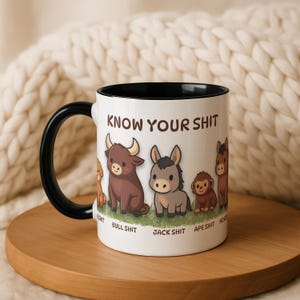 May include: White ceramic mug with a black handle and interior, featuring the text "KNOW YOUR SHIT" above cartoon animals. The animals include a dog, bull, donkey, ape, and horse, each labeled with a pun.