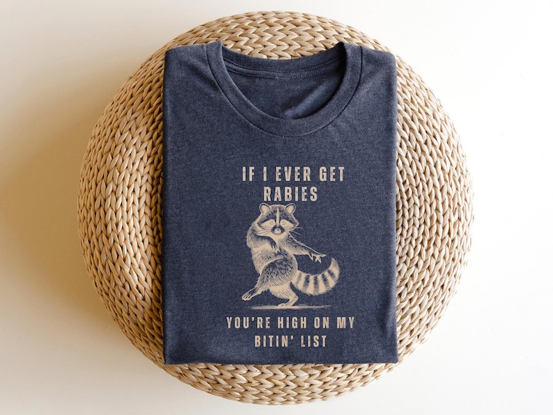 a blue t-shirt with a graphic of a raccoon and text that reads "If I ever get Rabies, you're high on my bitin' list".