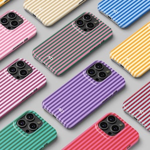 May include: A collection of colorful phone cases with vertical striped patterns. Cases are in various colors, including pink, green, purple, and yellow. Each case has a camera cutout and the initials "AD" printed on the bottom.