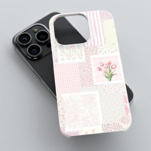 May include: A phone case with a patchwork design in shades of pink and white. The case features various patterns, including stripes, gingham, and floral prints. A square patch displays a watercolor illustration of pink tulips. The case is on top of a black phone.