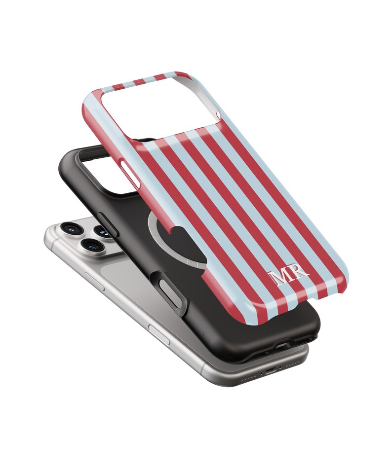 May include: A smartphone with a black case and a striped red and light blue phone case. The striped case has the initials "MR" in white. The phone is silver.
