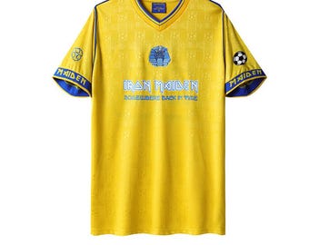 May include: A yellow V-neck jersey with blue trim and the text "IRON MAIDEN SOMEWHERE BACK IN TIME" in blue. The jersey has a repeating pattern and a soccer ball graphic on the sleeves. The sleeves also have the word "MAIDEN" in blue.