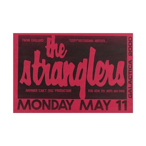 May include: A rectangular concert poster with a dark background and bright pink text. The text reads: FROM ENGLAND, STIFF RECORDING ARTISTS, THE STRANGLERS, ANOTHER CAN'T TELL PRODUCTION, FOR ADU. TIX. INFO. 443-2000, GALACTICA 2000, MONDAY MAY 11.