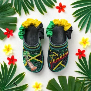 Può includere: Un paio di zoccoli neri decorati con i colori e i motivi della bandiera giamaicana. Gli zoccoli presentano dettagli verdi, gialli e neri, con la parola "Jamaica" in lettere colorate. Palme e altri elementi tropicali sono inclusi nel design.