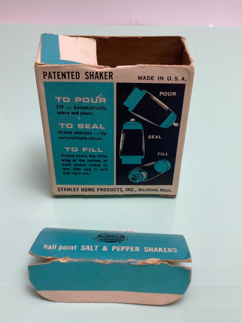 May include: Vintage salt and pepper shaker set in its original box. The box is rectangular with a teal and brown color scheme, featuring instructions and the text "PATENTED SHAKER" and "MADE IN U.S.A.". The box also includes a separate teal-colored lid.