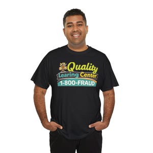May include: Black t-shirt with the text "Quality Learing Center 1-800-FRAUD" in yellow, green, and orange. The shirt has a crew neck and short sleeves. The text is centered on the front of the shirt.