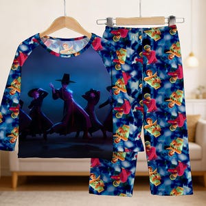 May include: A two-piece pajama set featuring a long-sleeved top and pants. The top has a dark blue background with a graphic of figures in traditional Korean attire. The pants have a repeating pattern of figures in red and green on a blue background.