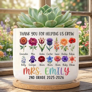 Puede incluir: Una maceta de cerámica blanca con el texto "THANK YOU FOR HELPING US GROW" y "MRS. EMILY 2ND GRADE 2025-2026". La maceta presenta ilustraciones de flores coloridas y nombres de estudiantes. Una planta suculenta se encuentra encima de la maceta.