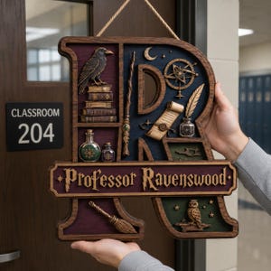 May include: A wooden wall hanging shaped like the letter R, featuring a dark finish and compartments containing a raven on books, a wand, a scroll, a quill, an inkwell, a broom, and an owl. A plaque reads Professor Ravenswood in gold lettering.