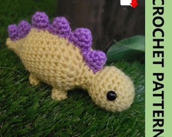 May include: A handmade crochet dinosaur toy in yellow and purple. The dinosaur has a rounded head, small legs, and a row of purple spikes along its back. The image includes the text "CROCHET PATTERN".