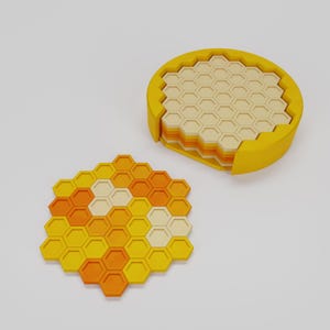 May include: A set of yellow, orange, and cream-colored hexagonal coasters. The coasters are arranged in a honeycomb pattern, with a matching holder. The holder is yellow and has a circular shape. The coasters are made of a solid material.