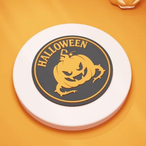 Könnte beinhalten: Ein weißer, runder Halloween-Untersetzer mit schwarzem Mittelteil. Das Zentrum zeigt ein Kürbis-Design in Orange mit dem Wort "HALLOWEEN" in orangefarbenem Text. Der Untersetzer liegt auf einer orangefarbenen Oberfläche.