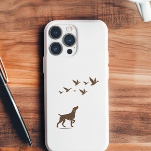May include: White phone case featuring a brown silhouette of a dog looking up at a flock of birds. The case has a glossy finish and a camera cutout. The design is simple and elegant, suitable for dog lovers and nature enthusiasts.