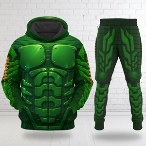 May include: A green hooded sweatshirt and matching sweatpants set featuring a printed graphic design of segmented armor plating with metallic rivets and a muscular chest plate pattern, complete with a dark gray hood lining and ribbed cuffs.