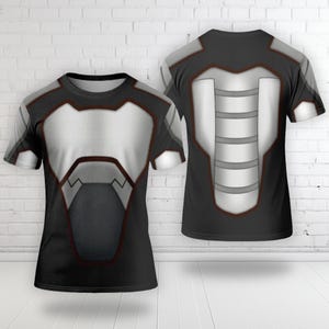 May include: A short-sleeved t-shirt featuring a graphic print of futuristic armor. The design includes black and silver-grey panels with dark red outlines, mimicking a chest plate on the front and a segmented spinal guard on the back view.